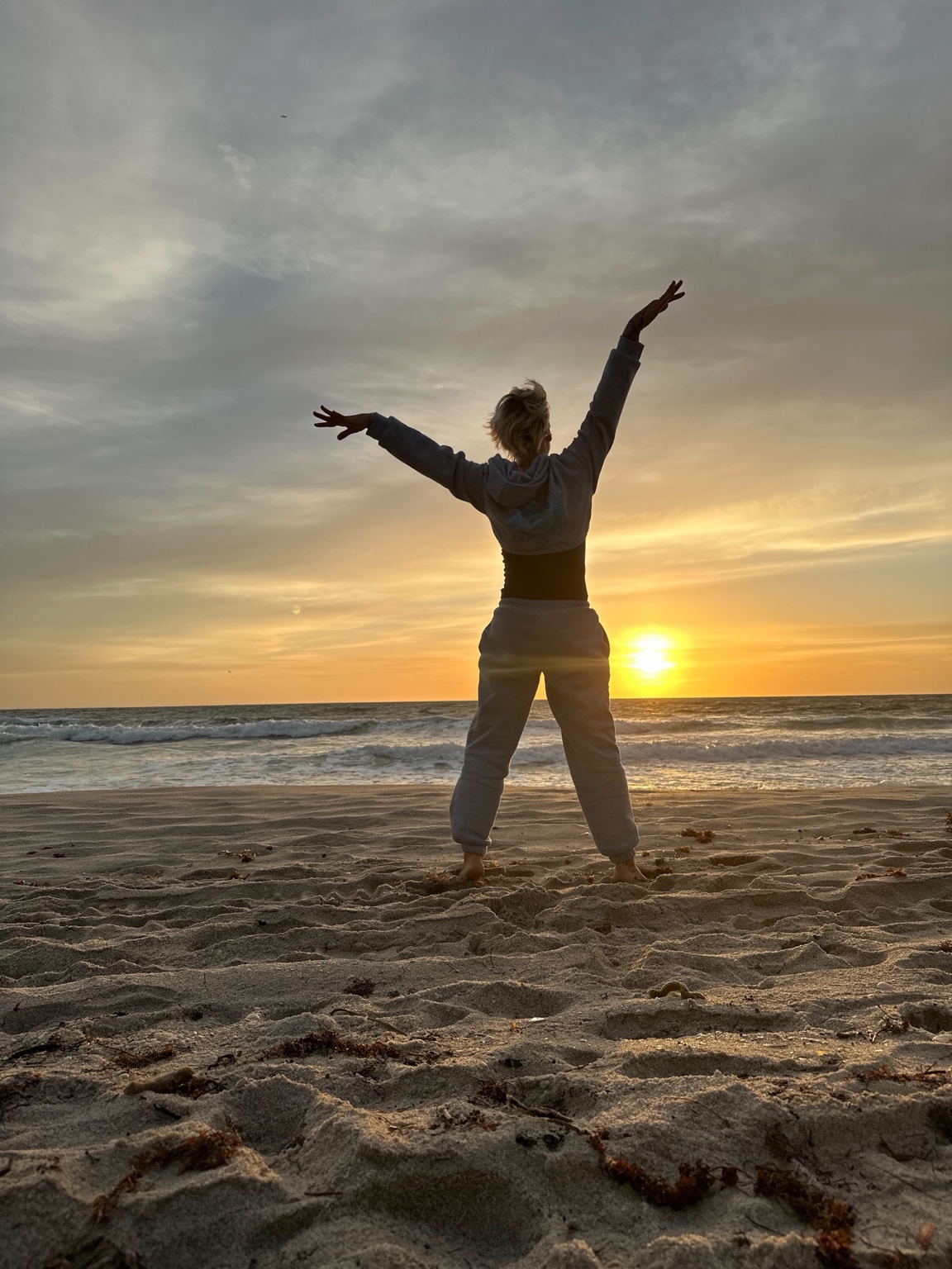 Gabriella practicing gentle Qigong beside the ocean at sunrise