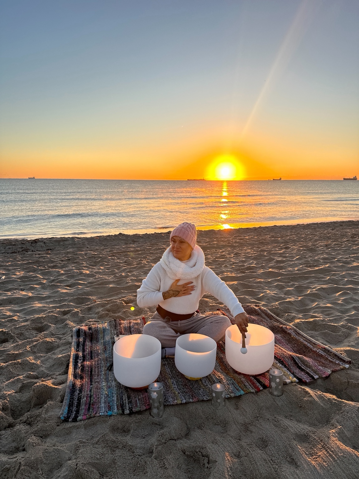 Gabriella with her crystal singing bowls on the beach at sunrise